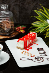 A slice of cheesecake with strawberry syrop on top with tea
