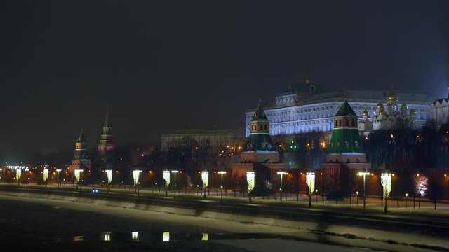 Moscow river is partially covered with ice. Embankment in front of the Kremlin wall. Ancient towers and a church with golden domes. Christmas decorations. Winter. Night time. Ultra HD