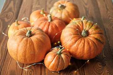 pumpkins with a shining garland on a wooden table