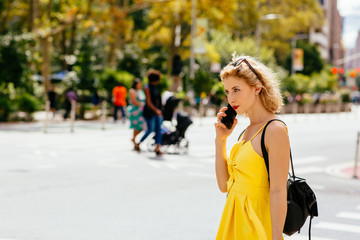 Young woman in yellow talking on the phone outside on the street