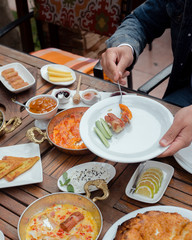 Man fulls his plate with sausage, egg dish from breakfast setup