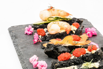 Mouillettes de pain noir au charbon et produits de la mer avec oeufs de lump  saumon fumé et gambas beurre et aneth pour oeuf à la coque sur un plateau en ardoise - isolé sur fond blanc