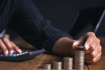 Men are Saint documents about save money and put coin in glass jar on desk on black background.