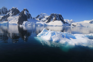 wystający ponad taflę wody wierzchołek góry lodowej przy wybrzeżu antarktydy w słoneczny dzień