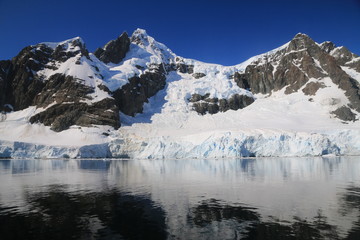 Obraz na płótnie Canvas spokojne zimne wody pomiędzy ośnieżonych skałami u wybrzeży antarktydy w piękny słoneczny dzień