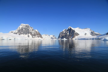 spokojne zimne wody pomiędzy ośnieżonych skałami u wybrzeży antarktydy w piękny słoneczny dzień
