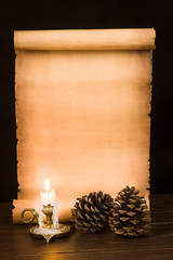 Scroll of parchment, pine cones and a lit candle