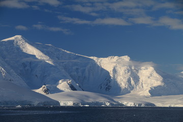 skaliste i ośnieżone wybrzeże antarktydy w słoneczny dzień - obrazy, fototapety, plakaty