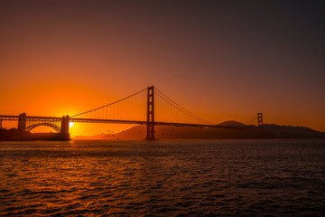Fototapeta na wymiar Red sunset at the Golden Gate of San Francisco with the sun hiding on the bridge. United States
