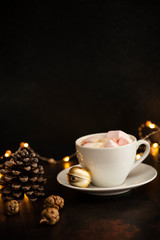 Warm cocoa drink with marshmallows. Christmas and New Year drink. Christmas Eve mood. Christmas lights and decorations. Winter holidays concept. Dark background. Vertical. Copyspace