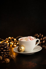 Warm cocoa drink with marshmallows. Christmas and New Year drink. Christmas Eve mood. Christmas lights and decorations. Winter holidays concept. Dark background. Vertical. Copyspace