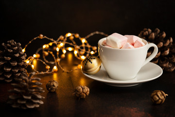 Warm cocoa drink with marshmallows. Christmas and New Year drink. Christmas Eve mood. Christmas lights and decorations. Winter holidays concept. Dark background. Copyspace