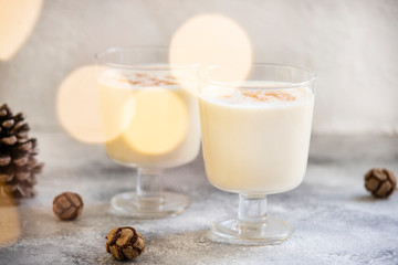 Eggnog traditional homemade Christmas and New Year drink with cinnamon and nutmeg. Winter holidays mood. Christmas lights. Light background. Selective focus