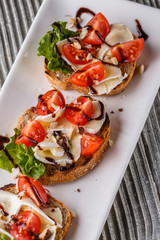 Bruschetta with tomatoes, lettuce, camambert, balsamic vinegar