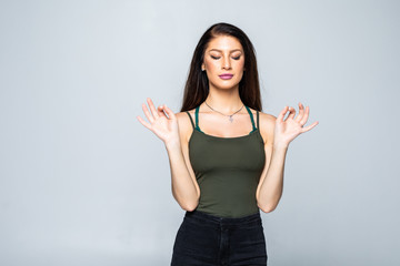 Yoga and meditation. Beautiful casually dressed young woman keeping eyes closed while meditating, feeling relaxed, calm and peaceful after hard working day at office, holding hands in mudra sign