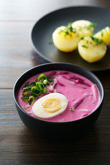 Lithuanian Saltibarsciai (Cold Beet Soup) with hard boiled egg and potatoes, seasoned with spring onions and dill. Dark wooden table, high resolution