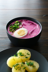 Lithuanian Saltibarsciai (Cold Beet Soup) with hard boiled egg and potatoes, seasoned with spring onions and dill. Dark wooden table, high resolution