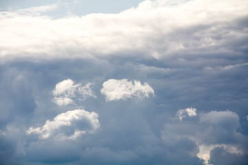 Bright clouds lit by the sun against the background of dark clouds. Natural background, cloudy weather