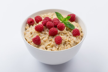Oatmeal porridge with fresh raspberries and mint on white background NOT isolated