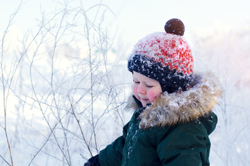 Portrait of a boy in a bright orange hat on the background of a winter Park