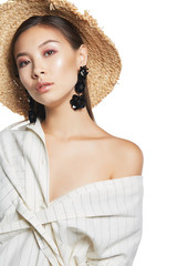 Medium close-up shot of young Asian girl in straw hat and white striped shirt wearing stud earrings made as a bunch of black paillette flowers with crystals.