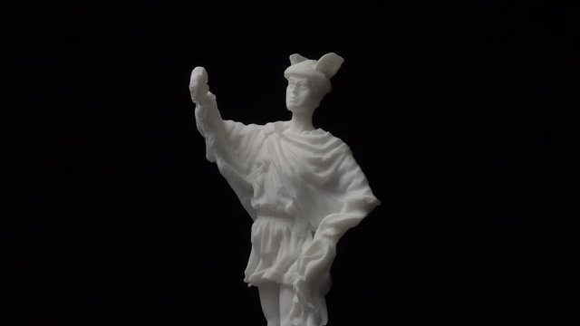Old greek white marble statue rotating against a black background. Hermes was god of trade, thieves, travelers, sports, athletes, and border crossings, guide to the Underworld.
