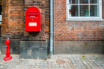 Red fire hydrant and red postal box against brick wall in Helsingor, Denmark