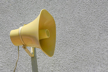 Yellow plastic Loudspeaker on the street on wall. The siren of air alarm.                 