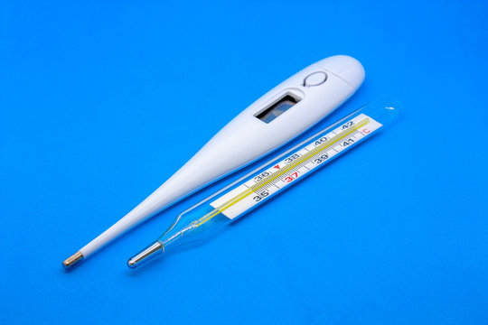 Mercury medical thermometer and electronic thermometer close-up on a blue background.