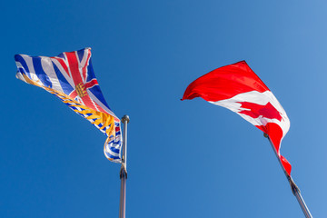 Looking up at the Canada and British Columbia (BC) flag blowing in the wind on a bright sunny day.