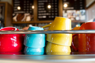 Heap of different ceramic cups on coffee machine in cafe.