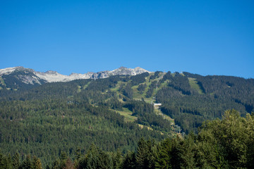 Whistler Mountain in British Columbia, Canada in the summer sun and blue sky looking at sky lift and runs used for mountain biking and hiking.