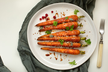 Baked organic carrots with honey, parsley, cheese and flax, pumpkin, sunflower seed on plarte. Top view. Organic vegan food.