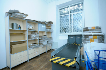 At the post office, view of the receipt and delivery room: belt conveyor, window and boxes with piles of letters and parcels