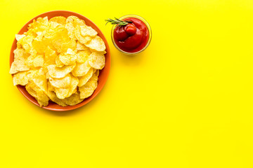 Homemade potato chips with ketchup for snack on yellow background top view copyspace
