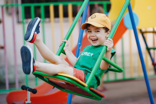 beautiful little boy spinning on a summer swing with space for text