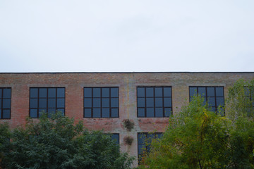 Bottom view of a brick building with large Windows and cloudy weather.