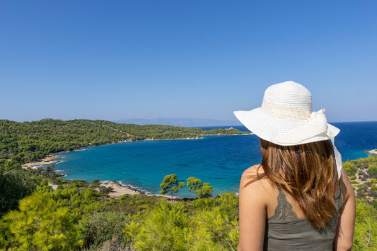 Young woman with hat looking at a beach on Spetses ISland near Hydra in Greece