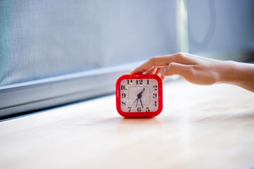 Hand and red alarm clock that shows the alarm at all Every morning, the concept of punctuality