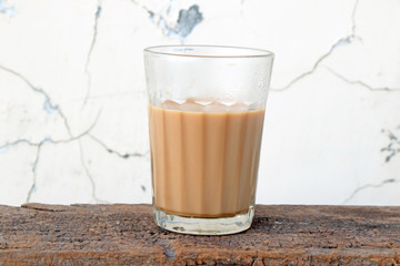 A glass of tea placed in a table with raw spices and rough wall in the background