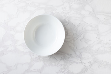 A white bowl on a marble surface. Overhand.