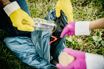 Team of friends cleaning up the park by collecting litter into plastic bags