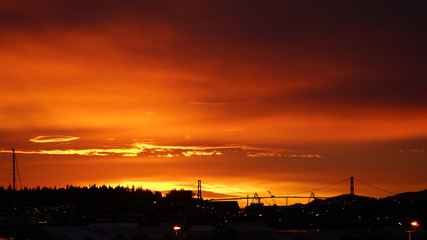 Red sky at night. Silhoutte view of North Vancouver Shipyards and LionsGate Bridge against fiery sunset