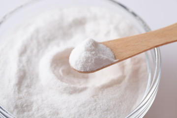Fototapeta na wymiar Chemical powder on a wooden spoon aspartame E951 over a bowl