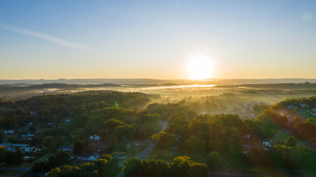 rays of sunshine illuminate fog  rising in the morning light