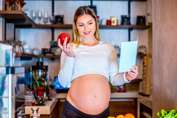 Young beautiful pregnant girl eating fruits in her home during daytime