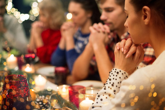 holidays and religious concept - close up of friends having christmas dinner and praying before meal