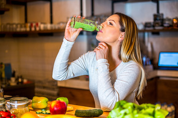 Young beautiful pregnant girl drinking smoothie in her home during daytime