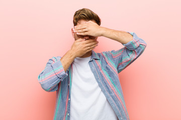 young man covering face with both hands saying no to the camera! refusing pictures or forbidding...