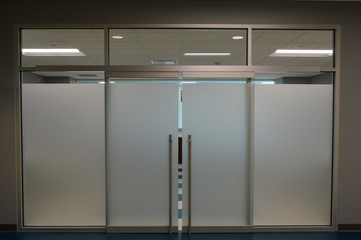 a neat and clean office space with a modern glass doorframe